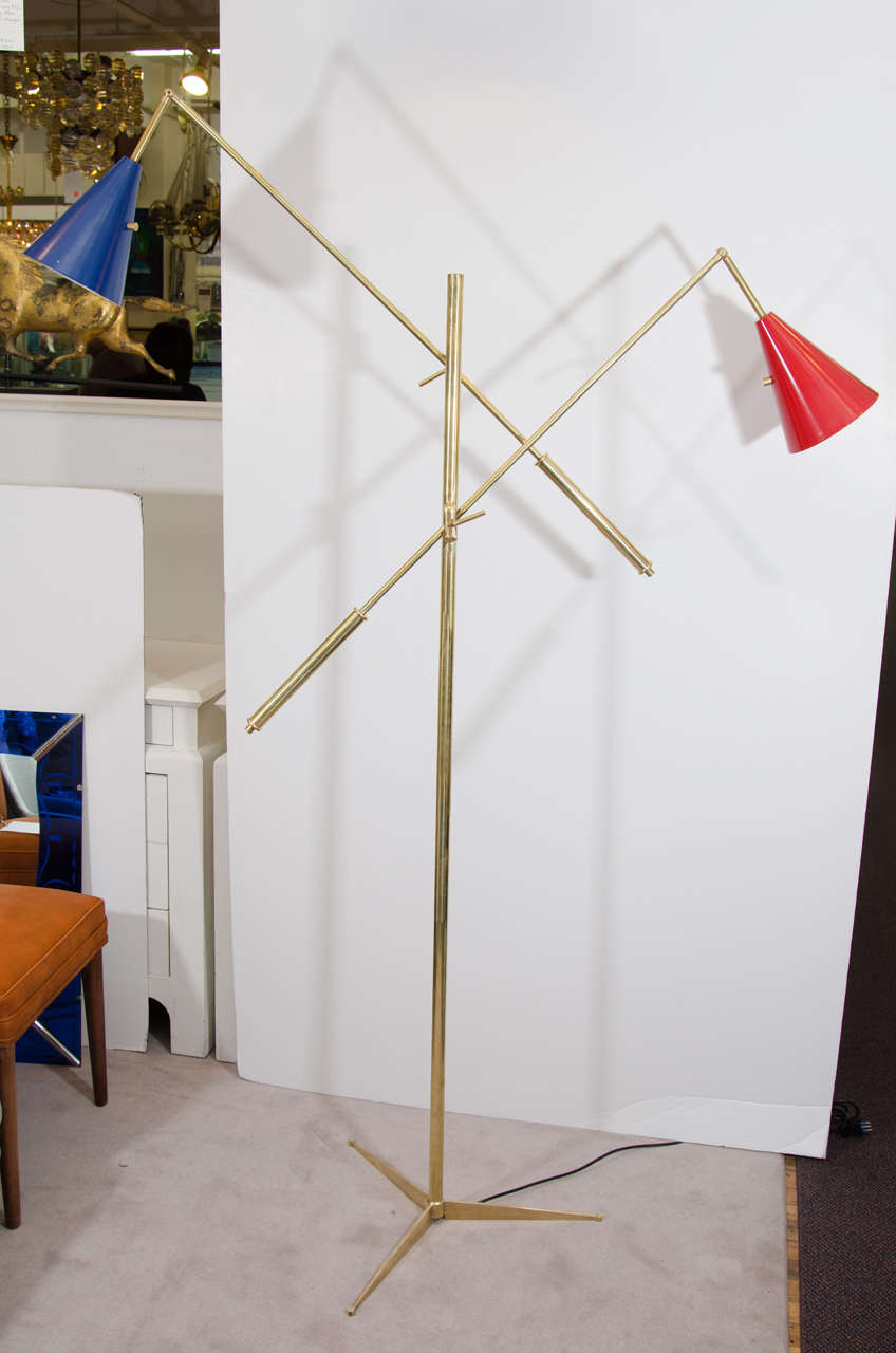 A vintage two-arm adjustable Italian brass-plated tripod base floor lamp with enameled shades in red and white. Good vintage condition with age appropriate wear and patina. Tiny nick to blue shade. European sockets and wiring.
