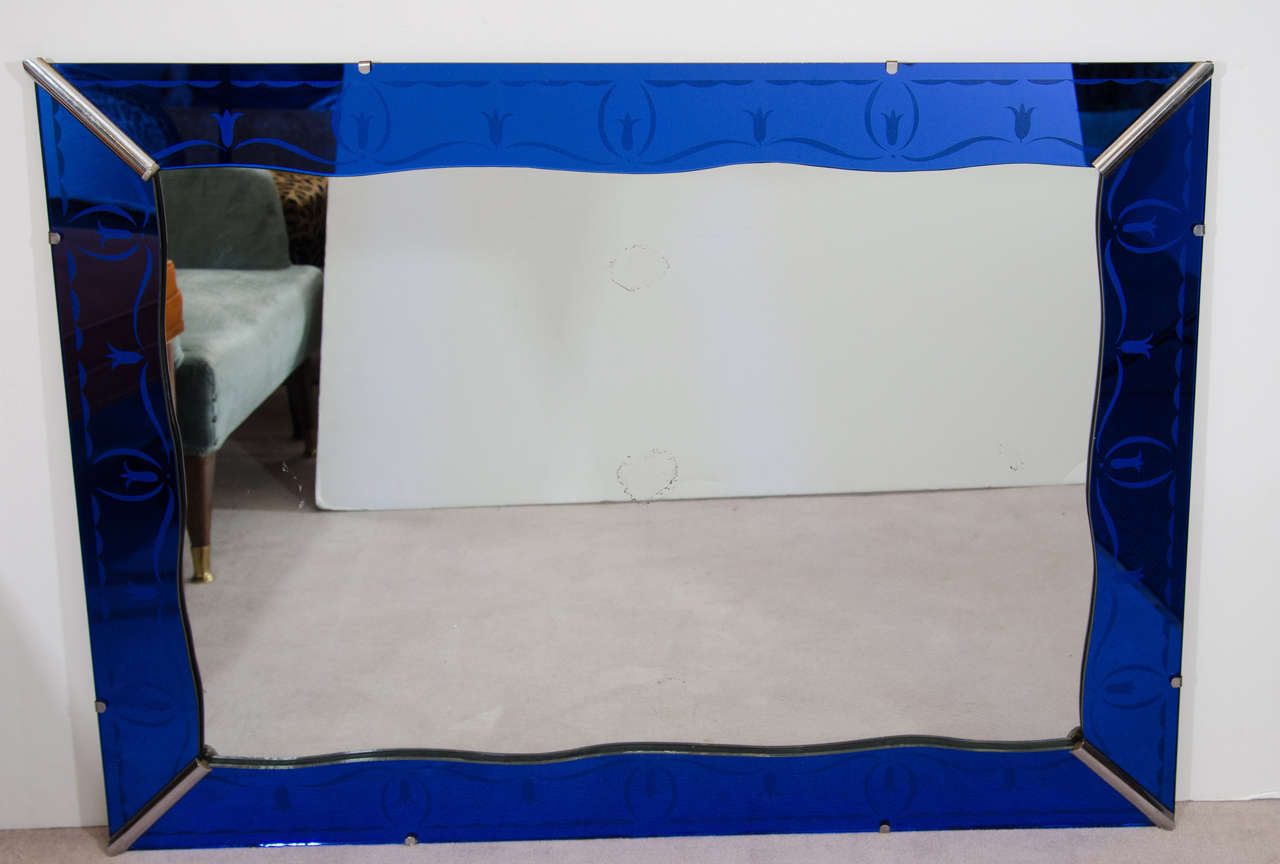 An Art Deco cobalt blue wall mirror with a scalloped edge. The frame has an abstracted etched floral design. Good vintage condition with age appropriate wear.

Some silvering.