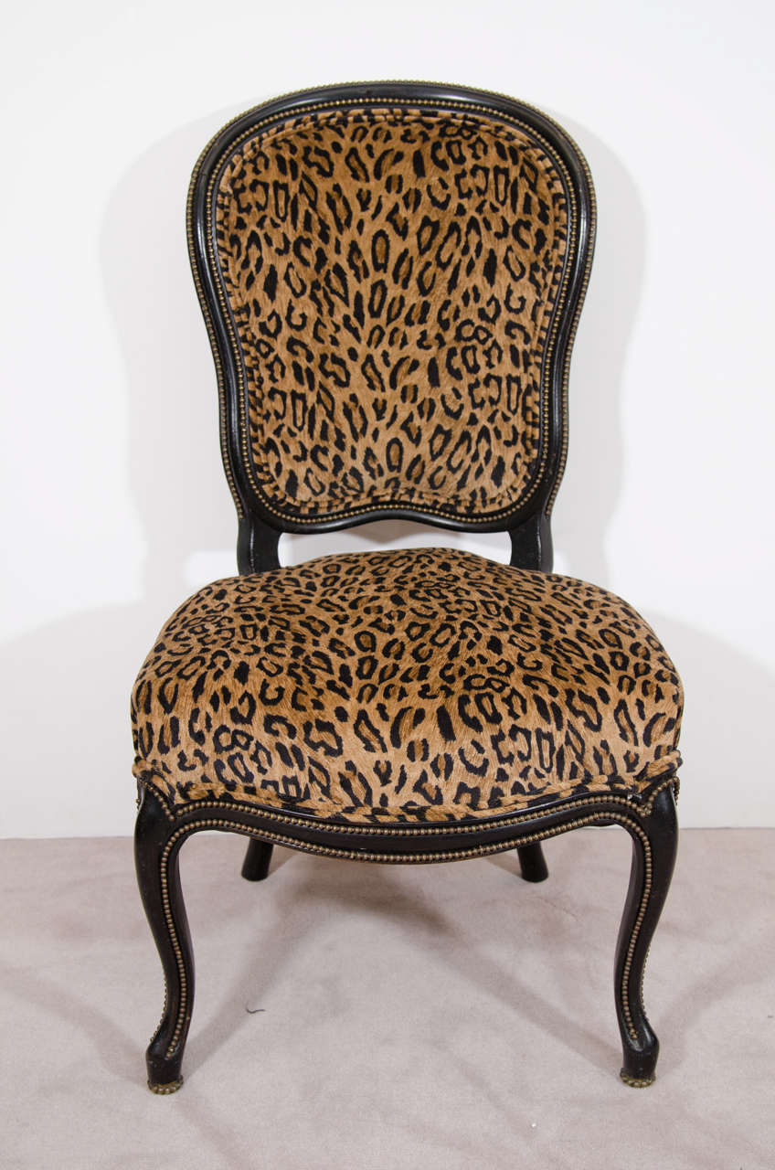 A pair of 19th century slipper chairs with ebonized frame, brass beading and newly upholstered in velvet leopard print.