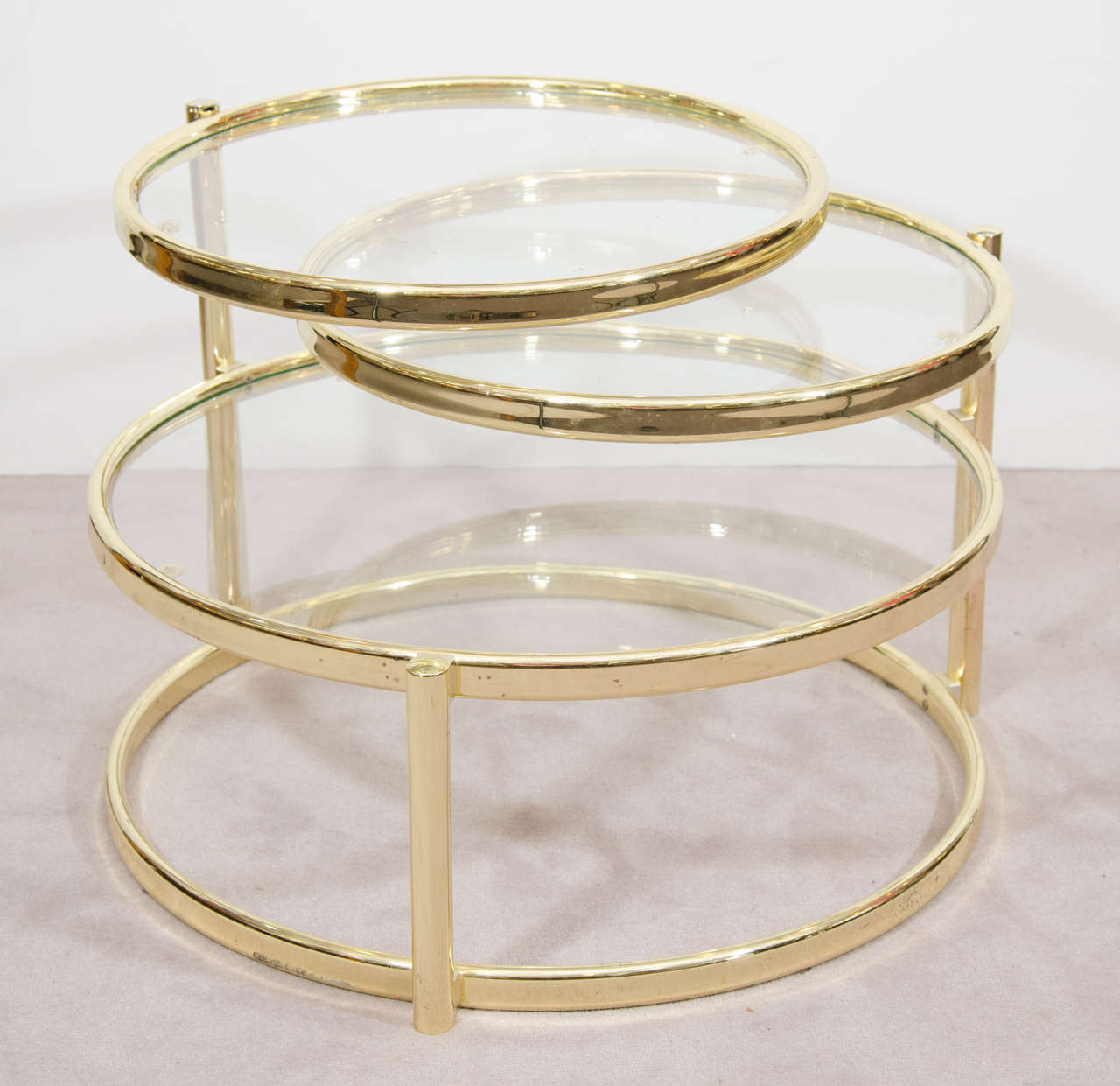 A vintage Milo Baughman inspired three-tier brass and glass swivel coffee table or cocktail table. The top two tiers of this versatile table pivot to expand to a width of 62 inches. It can function as a side table when closed or a coffee table when
