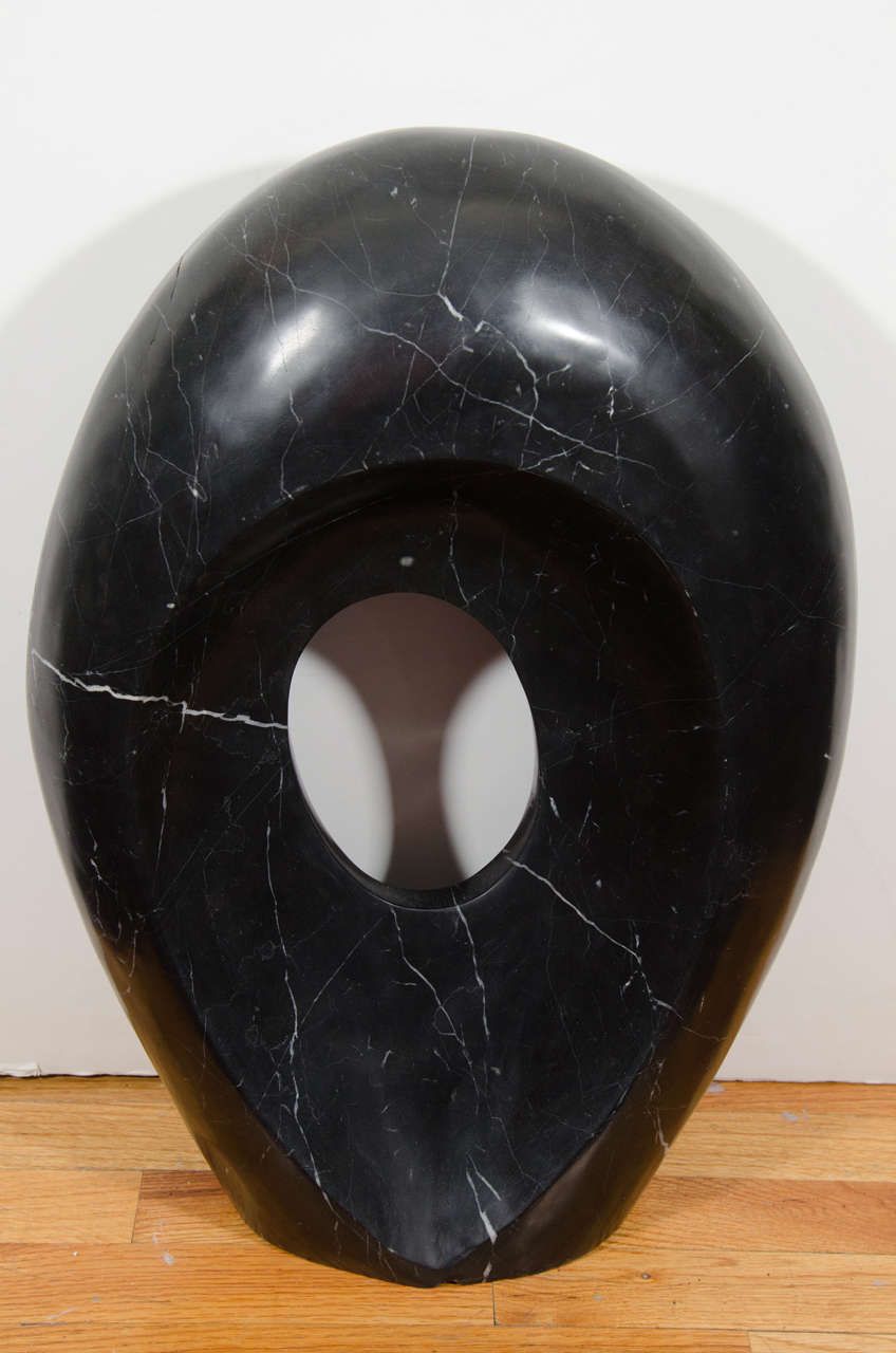 A contemporary oval sculpture in black marble with white veins signed Kelly Wearstler. Good condition with a few cracks.