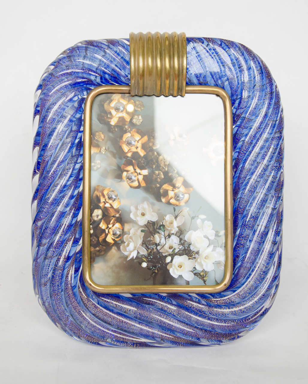 Smooth sculpted frame of twisted glass patterned with blue and gold,
Swirls. Brass surround and support. Signed: Barovier and Toso.