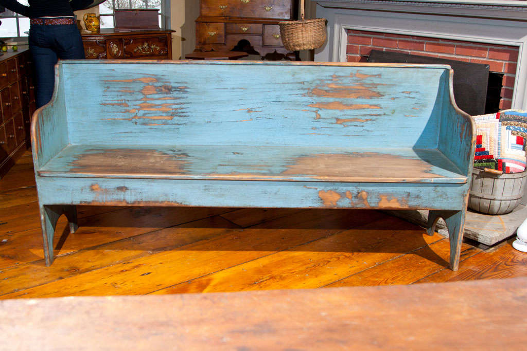 A very handsome and hand planed plank wood bench. This bench exudes a warm & cozy patina in a blue painted surface. Wide plank board construction with entirely hand tooled surfaces and simple half moon feet.  This bench makes for perfect seating in