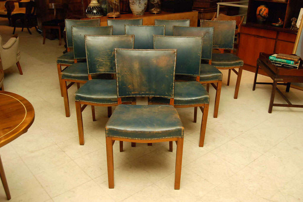 Set of 10 Danish modern dining chairs in the manner of Kaare Klint, upholstered in blue leather with saddle form seat and brass studding.  Oak frames, leather faded to a blueish brown with wear and  age