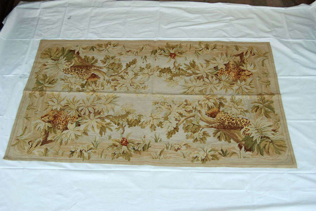 This smart needlepoint rug from an original design is subtle but dramatic in composition. Designed as an all over foliate design with cheetahs in trees emanating from the four corners. The rug is large enough to be used under a glass coffee table or