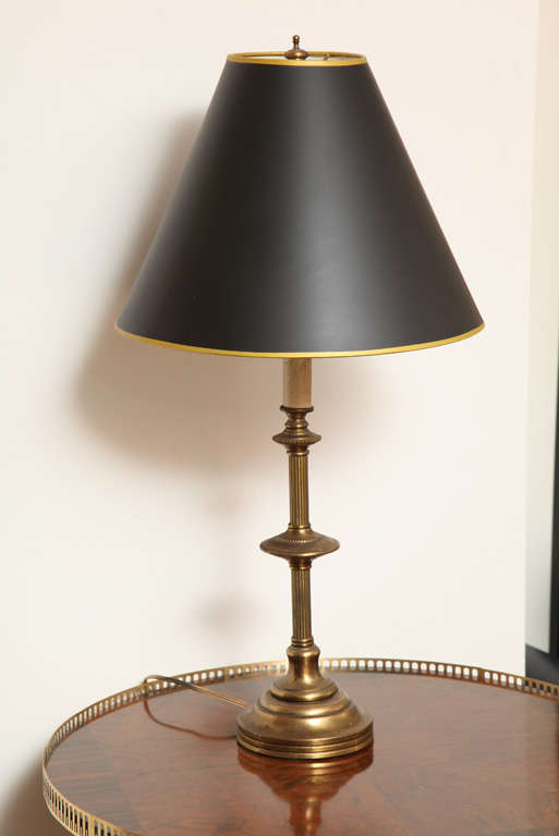This aristocratic table lamp is a beautiful antique from England. Its has been updated with lamp shade in black and gold trim. It has original bronze patina.