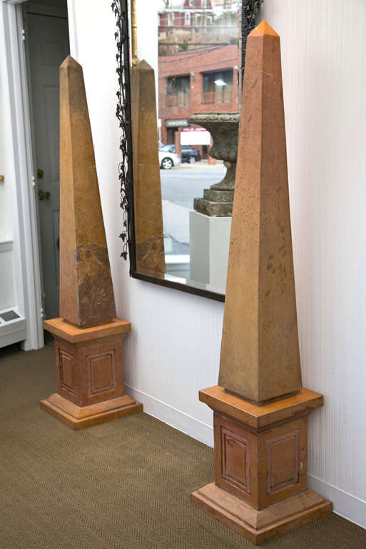Pair of unique solid marble obelisks having pyramidal tops and stepped bases in caramel brown tones.