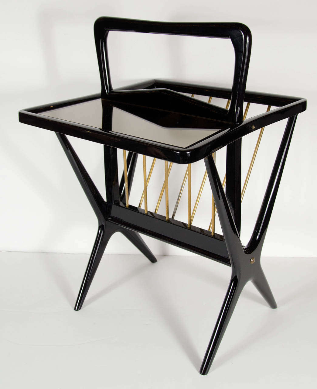 This piece is such a great unique design. It features a magazine holder with brass supports and the other side has a table shelf support in bronze mirror.It has a great splayed leg design ,handle and is made of ebonized walnut.This piece has been
