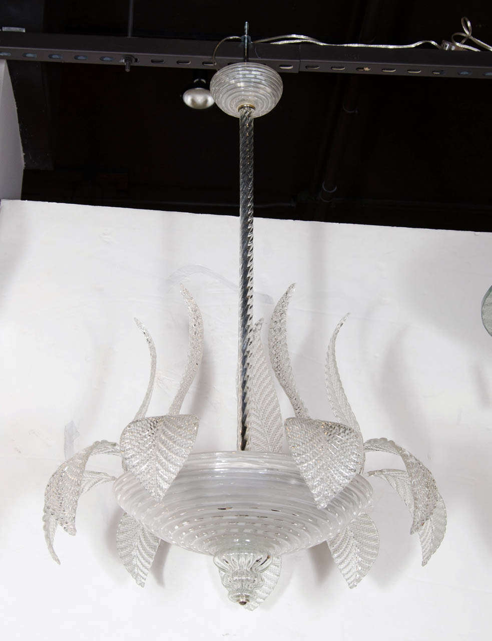 This exquisite chandelier is made of hand blown murano glass with 24k white gold inclusions.The central dome features a three tier blown glass finial detail with the foliate leaf plumes emanating  outwards. The central stem is twisted hand blown
