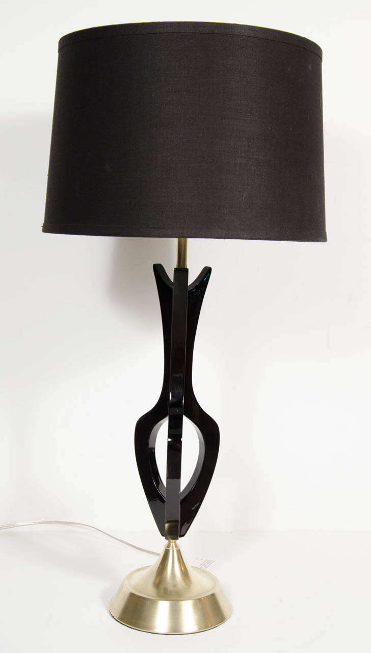 These very sophisticated lamps feature an hourglass shape made from a floating frame of brass supports with suspended ebonized walnut accents. Newly rewired with custom shades.