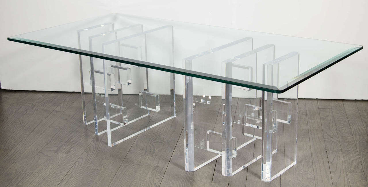 This Mid Century Modern cocktail table features a lucite base composed of multiple lucite forms, creating a wealth of dynamic geometries, and a beveled glass top. With its bold forms and clean lines, this piece represents 1970s American design at