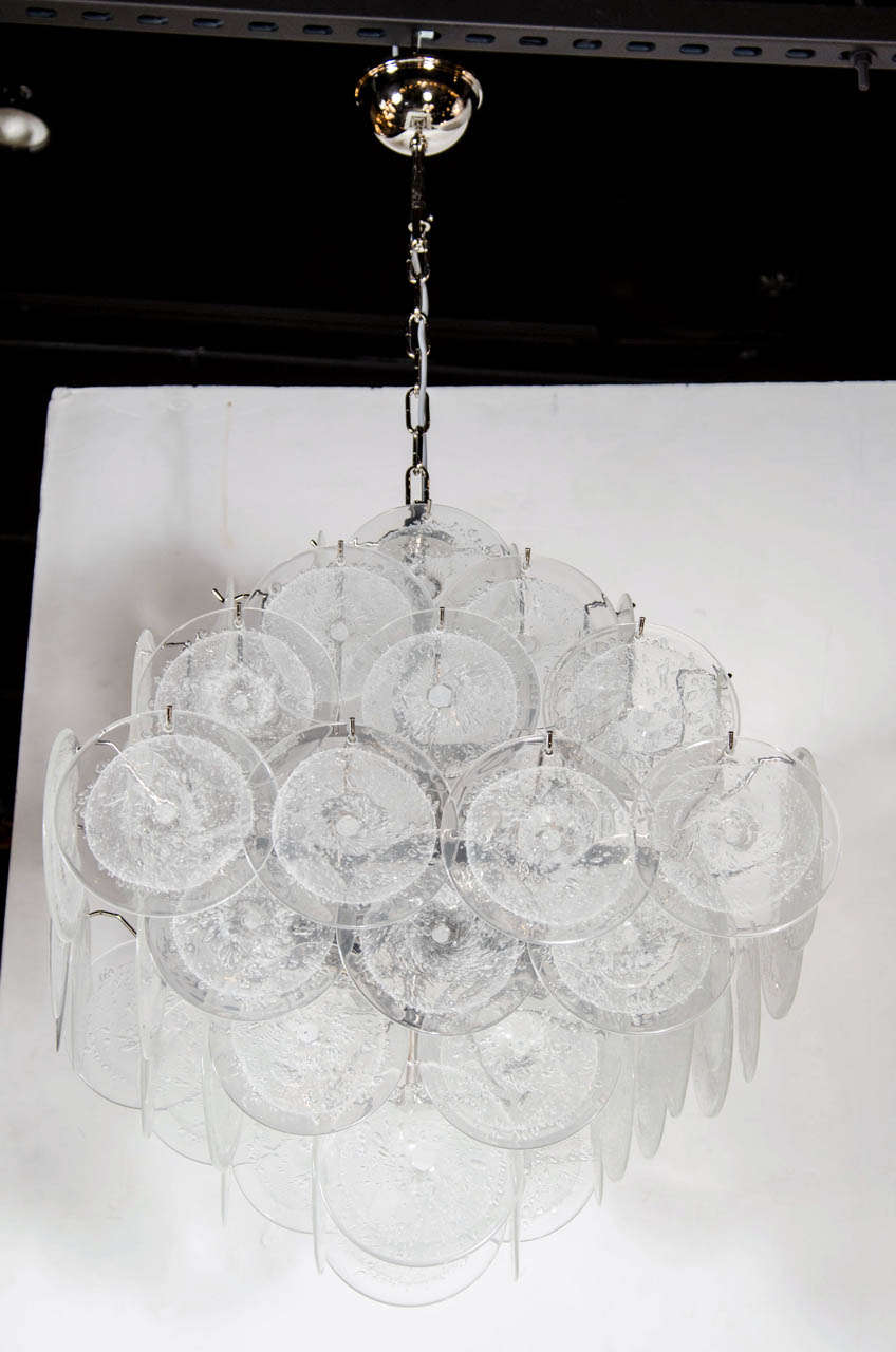 This stunning chandelier was hand blown by artisans in Murano, Italy- the island off the coast of Venice renowned for centuries for its superlative glass production. It features 62 Murano Glass Discs suspended in a diamond formation, from a polished