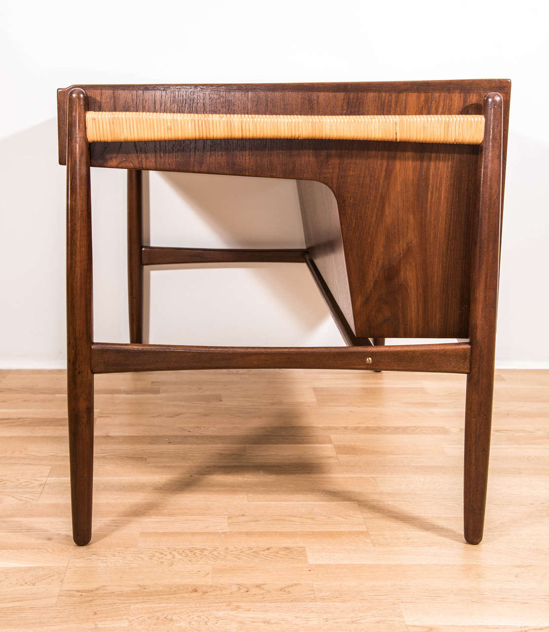 A gorgeous and unique designed writing desk in teak wood with cane wrapped side arms,
open back storage and finished in a rich walnut color..