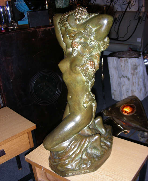 Patinated bronze statue representing a kneeling nude woman holding grapes, by Maxime Real del Sarte, titled 