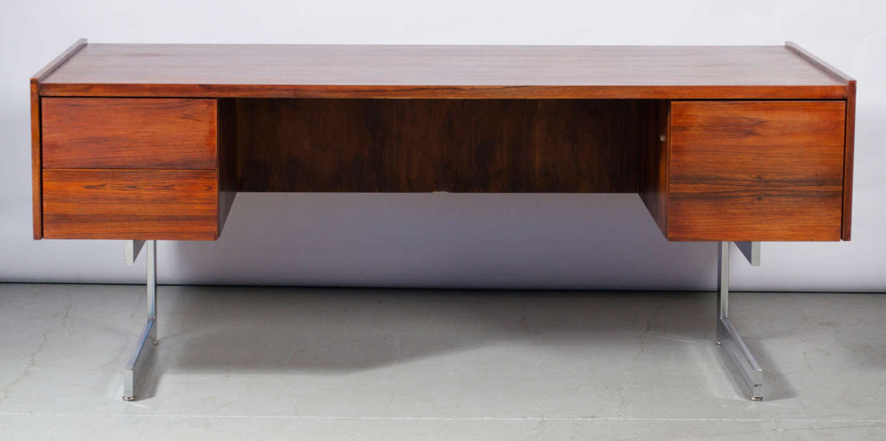 An Executive desk of rosewood and chrome by Milo Baughman. Features a floating, 