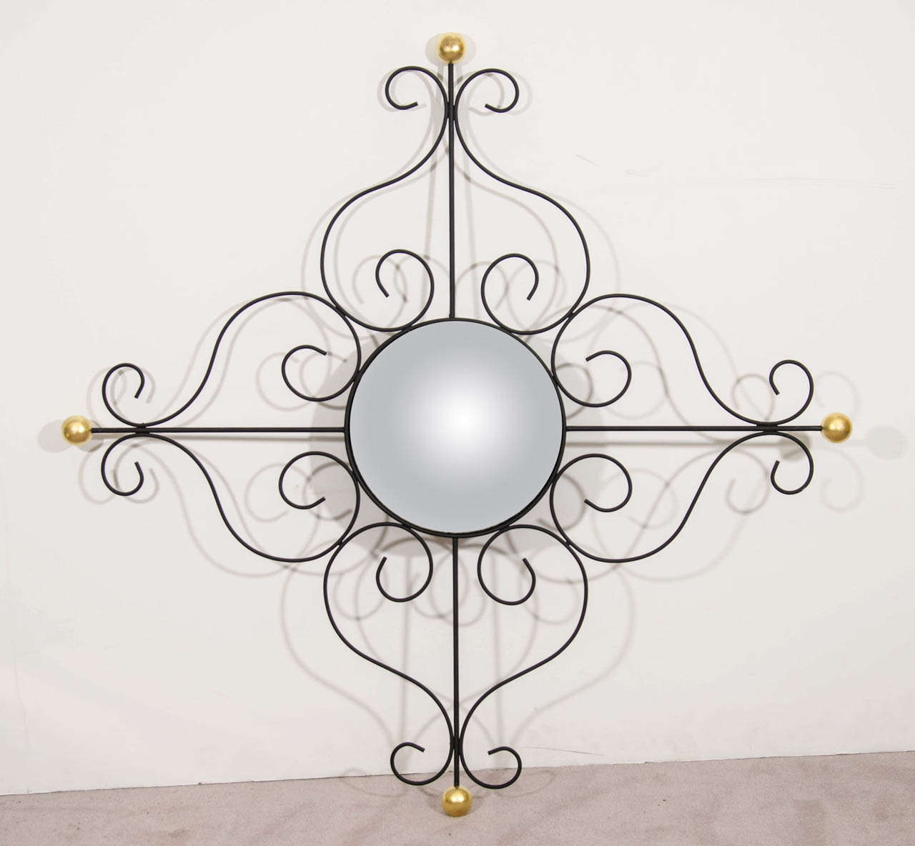 A vintage convex wall mirror with black scrolled iron frame in French modern style with 18-karat gold leaf ball accents.