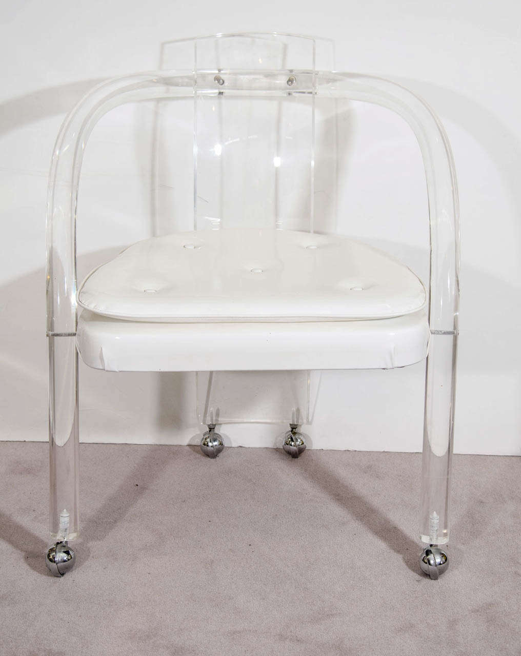 A vintage set of four patent leather and Lucite armchairs on casters by Hill Manufacturing.  

The chairs are in vintage condition with some scratches.  One chair has a some stress fracturing.  There are also marks on some of the white cushions,