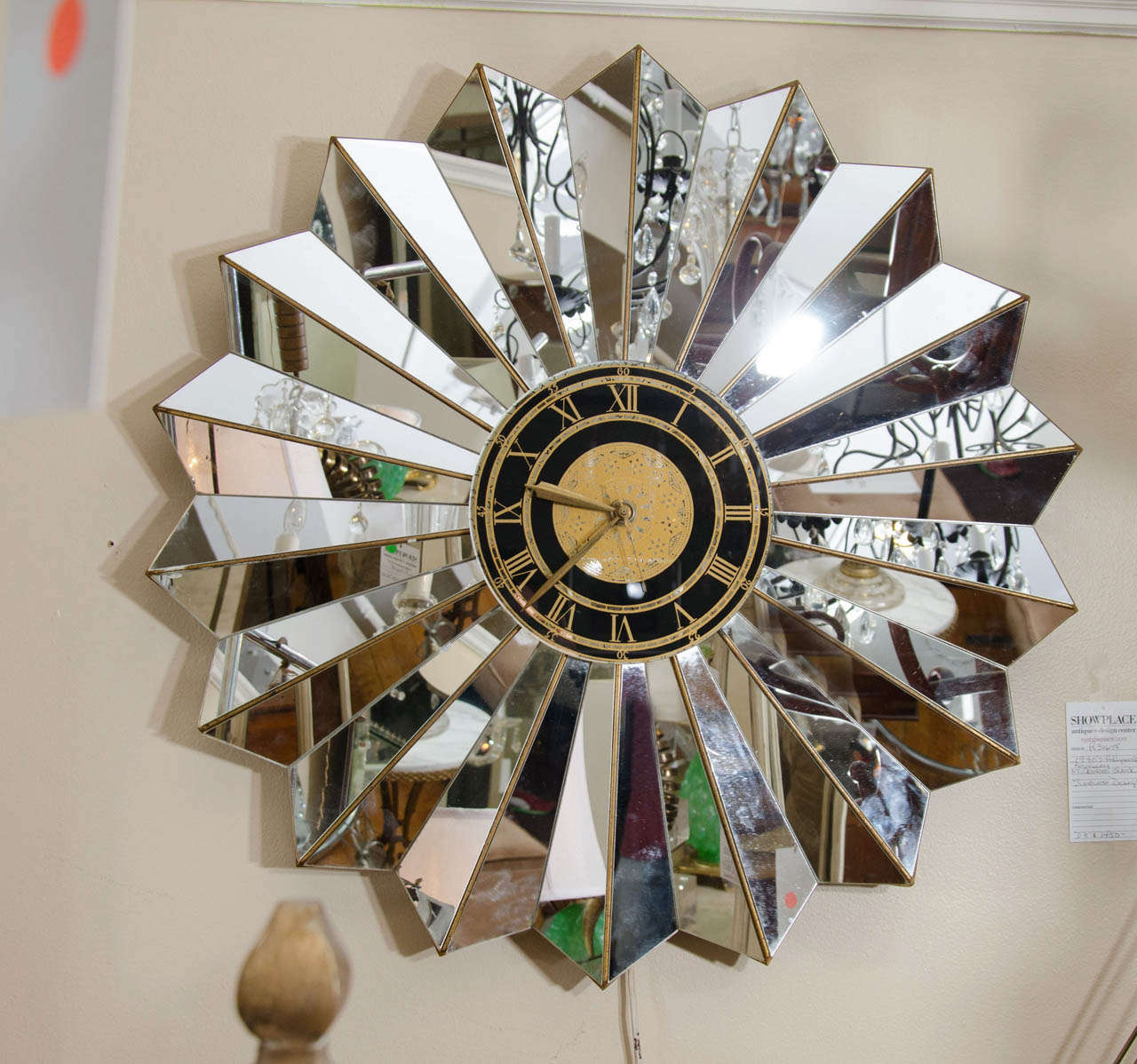 A Hollywood Regency style wall clock in the shape of a starburst with mirrored, antiqued glass.  This clock is in working condition.