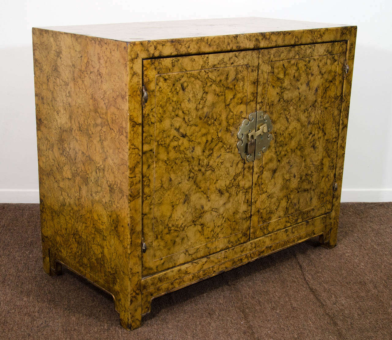 A vintage Asian-inspired two door cabinet with brass detailing and Faux tortoise finish. 

Vintage condition with some wear around the edges.  There are some nicks and scratches along with small cracks to the surface.