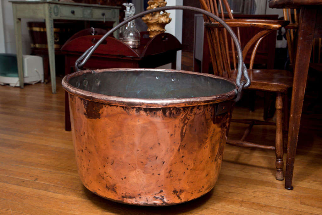 A large copper apple butter kettle with a hand wrought iron bale handle.