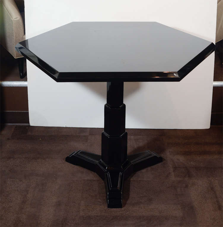 Art Deco center table in a

black lacquered finish. The 

table has a hexagon shaped

top with chamfer detailed 

edges and a tripod base

with stepped details,

and skyscraper pedestal

design. Makes a terrific 

game table or