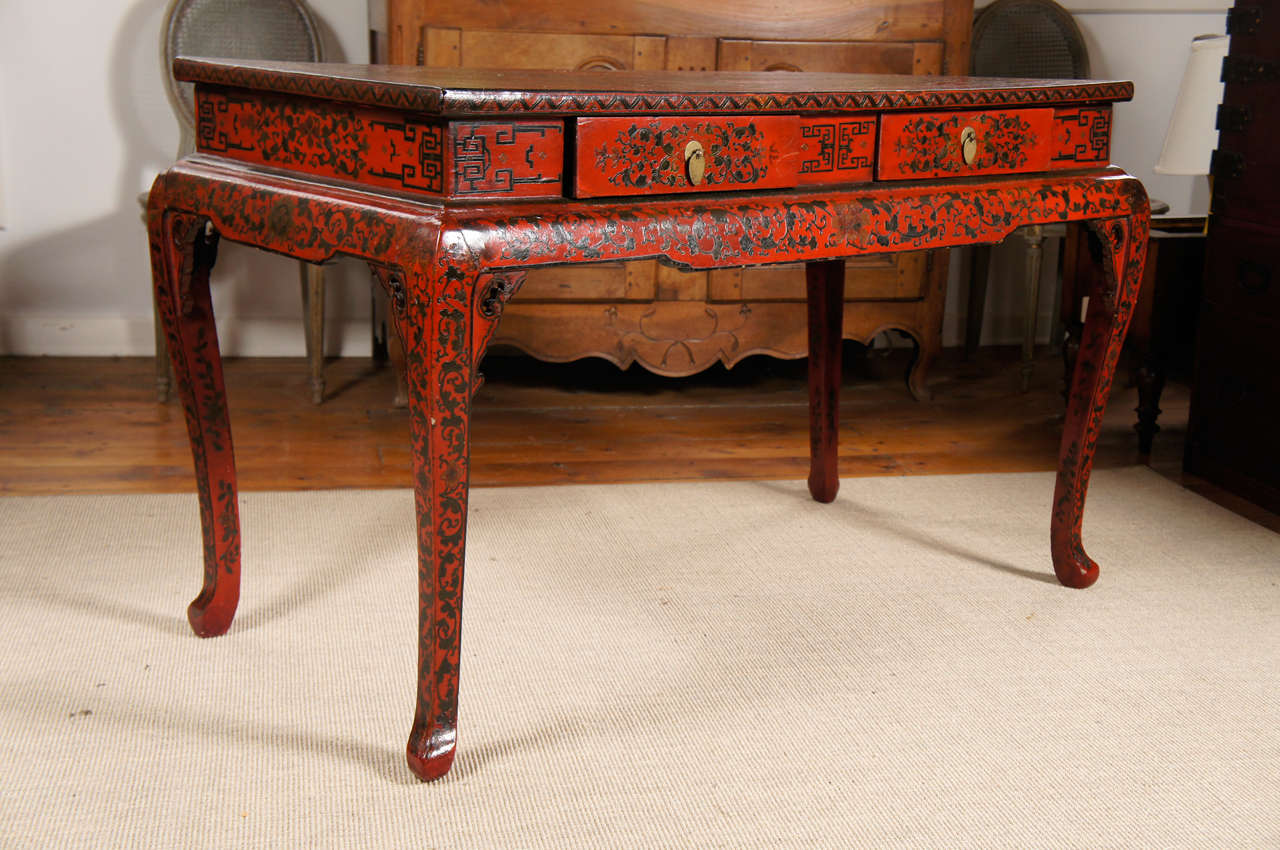 Beautiful Chinese red lacquer console table. The top having a landscape scene within a cartouche surrounded by a border of foliate decoration and two drawers. The base with a shaped apron and four cabriole legs with pointed pad feet.