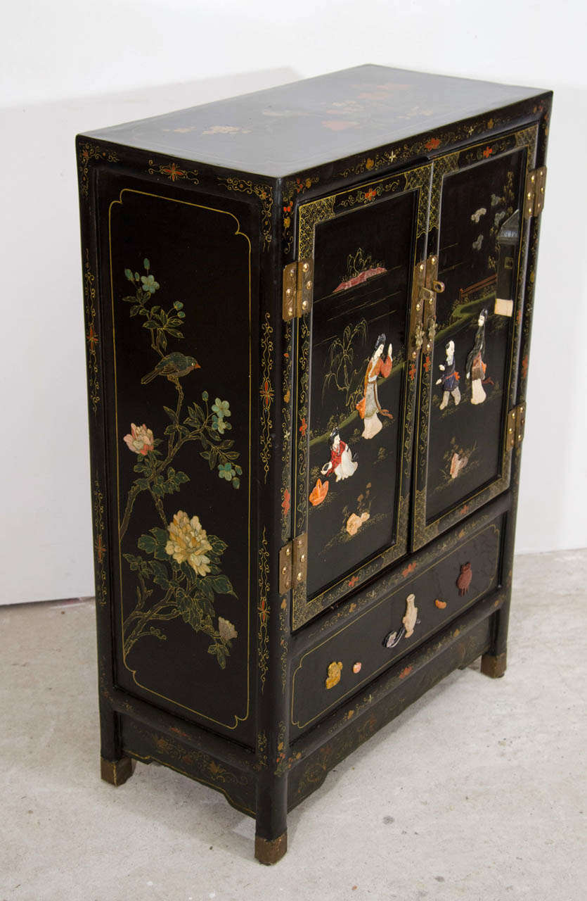 A  20 century Japanese black lacquer side cabinet. Decorated with figures amongst landscapes to both the upper cupboard and the larger lower cupboard section.