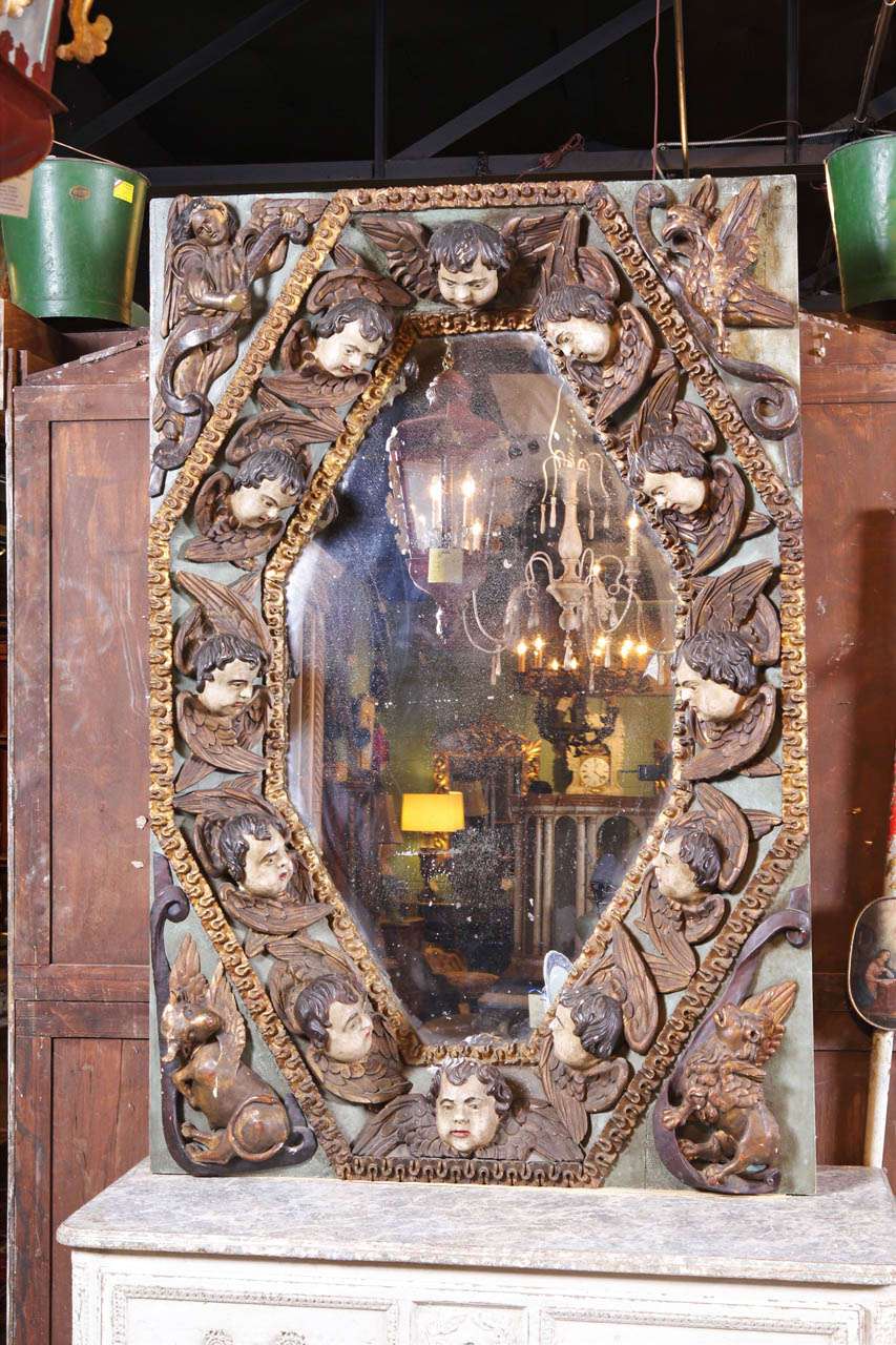 Originally, this unique painted mirror was probably in a private chapel or a small Spanish church. It features 12 carved angels faces around the perimeter of the antique mirror. The paint is original with vibrant colors.