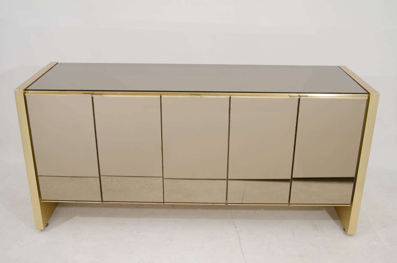 Beautiful Ello credenza with smoked, bronze tinted mirror top and doors. The cabinet is accented with satin brass side panels and trim. Very chic! Note: This piece has been reduced from $5,950 because it is missing interior shelves. An easy solution