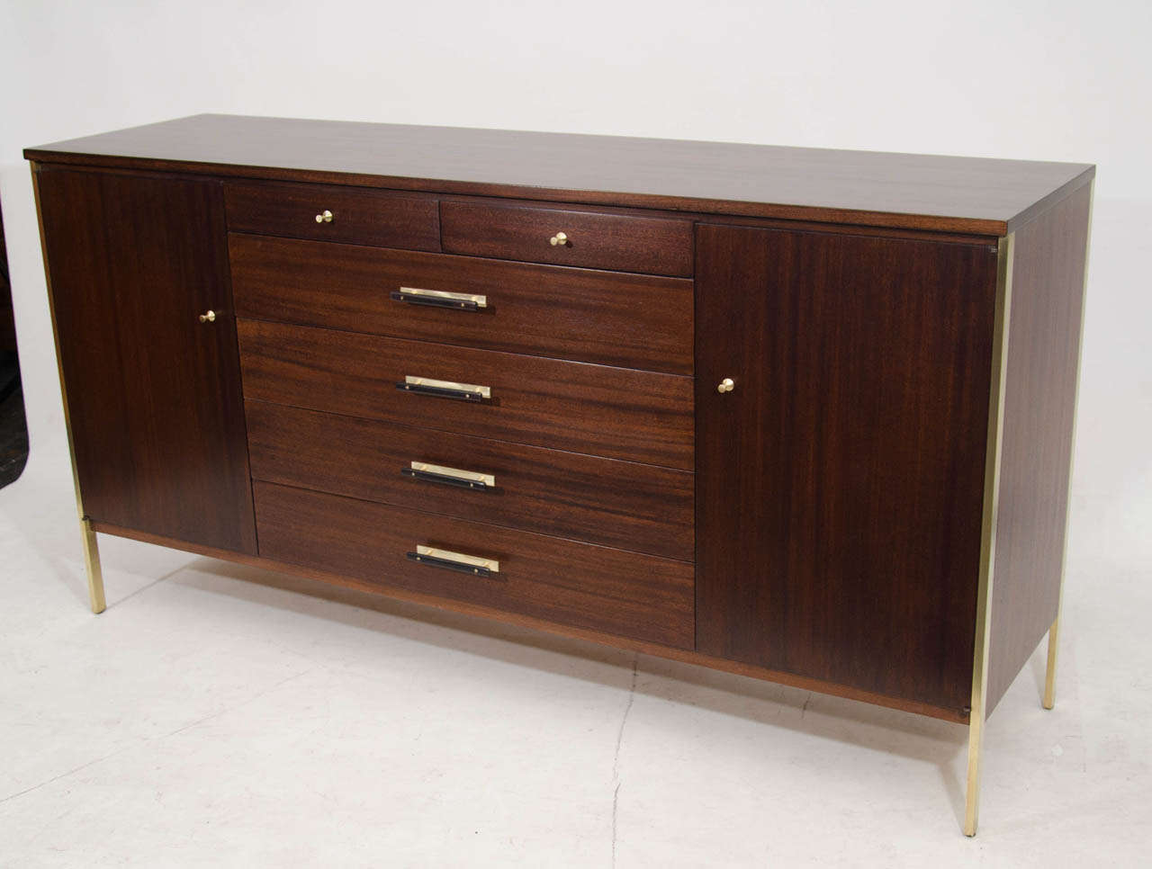 Very handsome dresser or credenza by Paul McCobb for the Calvin Group. Beautifully refinished in a rich brown stain and accented with brass frames that extend to the floor. Aspecial feature are the horizontal wood and brass pulls. Quite Nice!