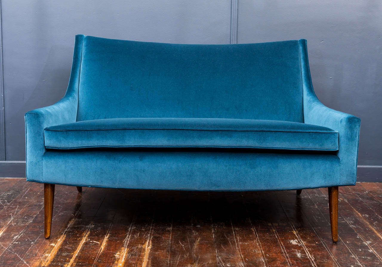 Art Deco small love seat with graceful lines and elegant walnut feet. Newly upholstered in iceberg blue velvet, simple elegance.