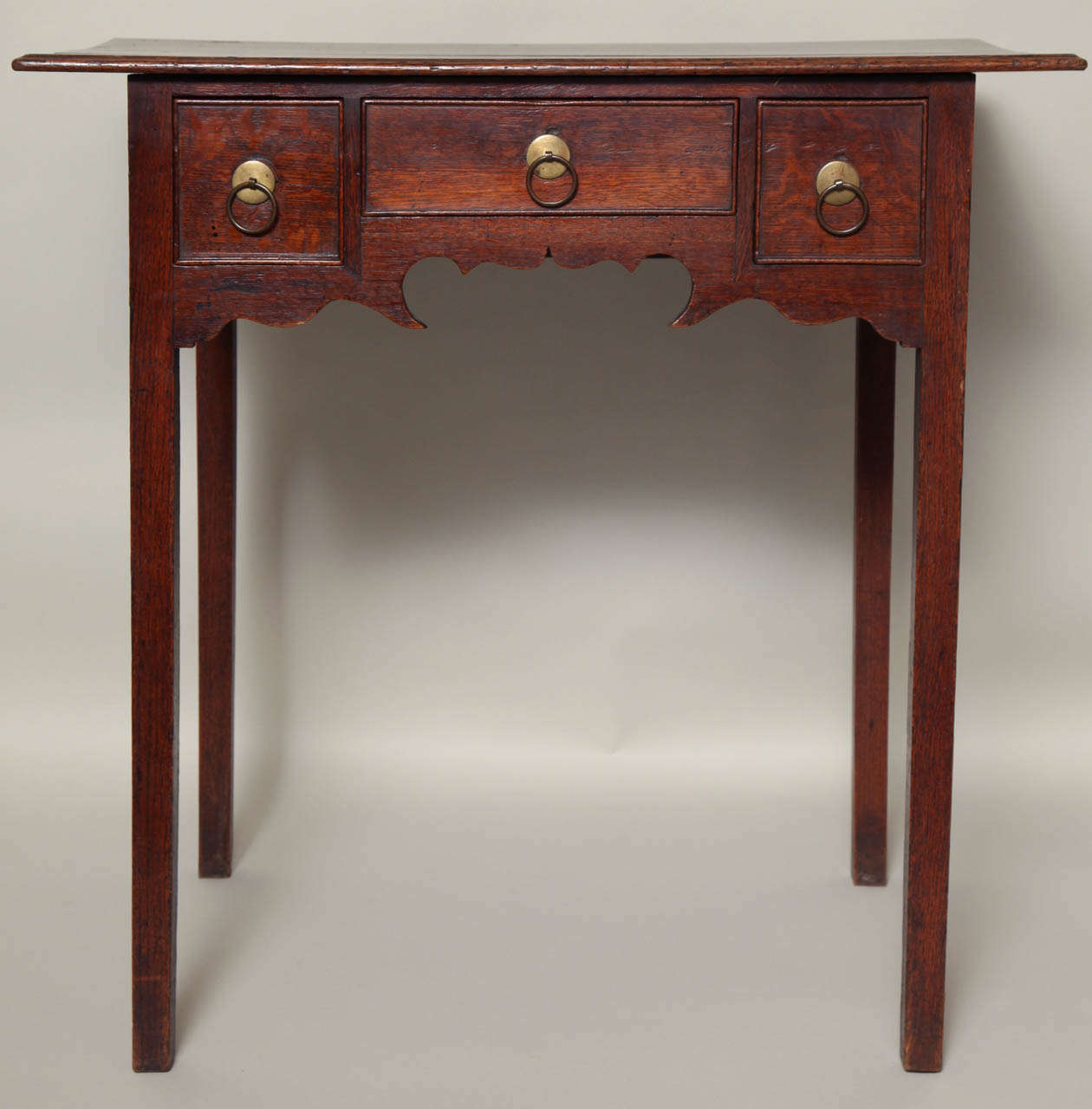 18th Century English or Welsh oak lowboy of unusual design, the nicely overhung molded top over two small and one wide drawer, standing on graceful high legs, the scalloping extremely whimsical in nature, having original  ring handles and possessing