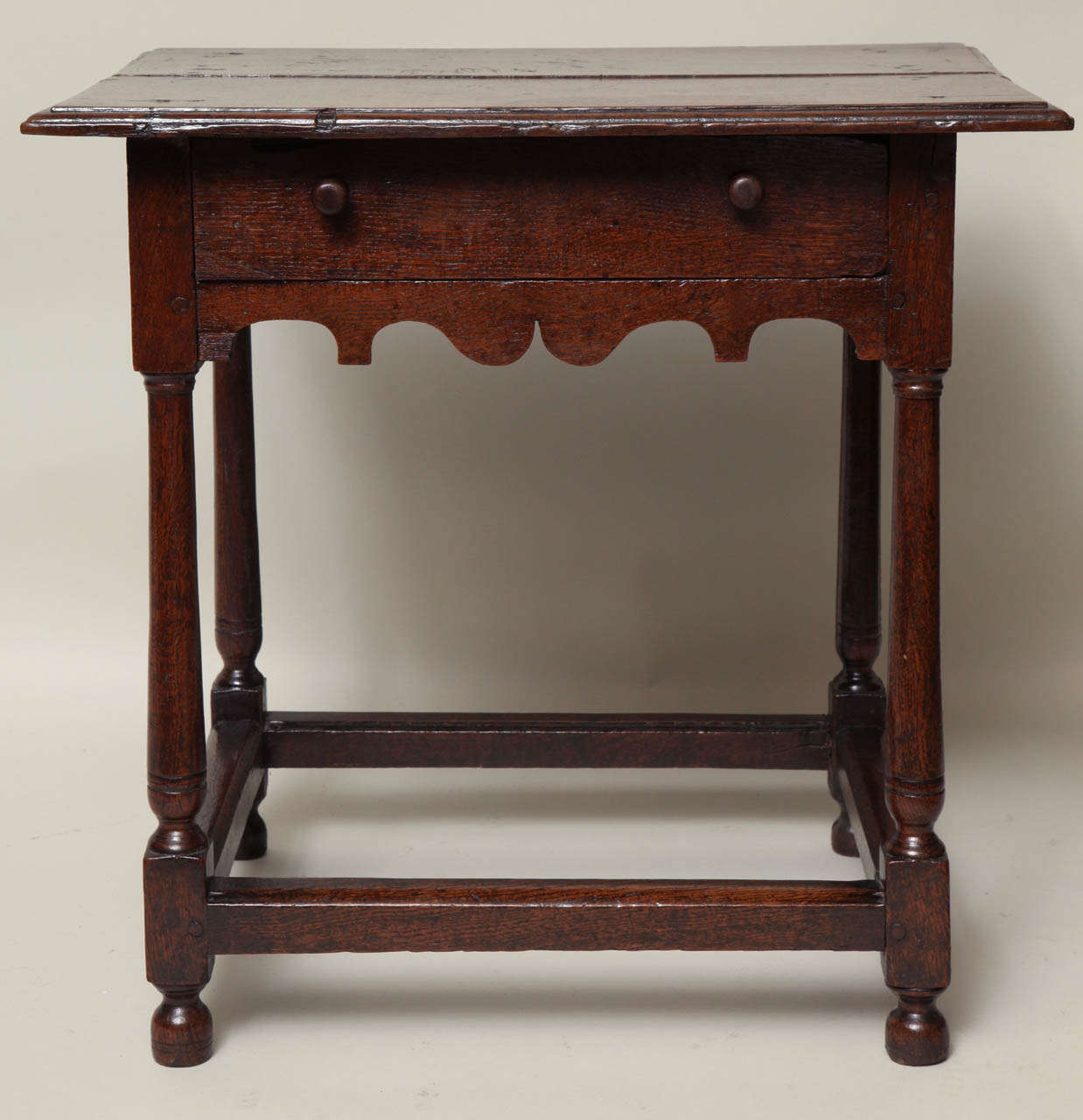 Good early 18th Century English oak single drawer side table, the thumb molded two plank top over single drawer having original turned fruitwood knobs, over cannon barrel legs joined by box stretcher, standing proud on original turned bun feet, the