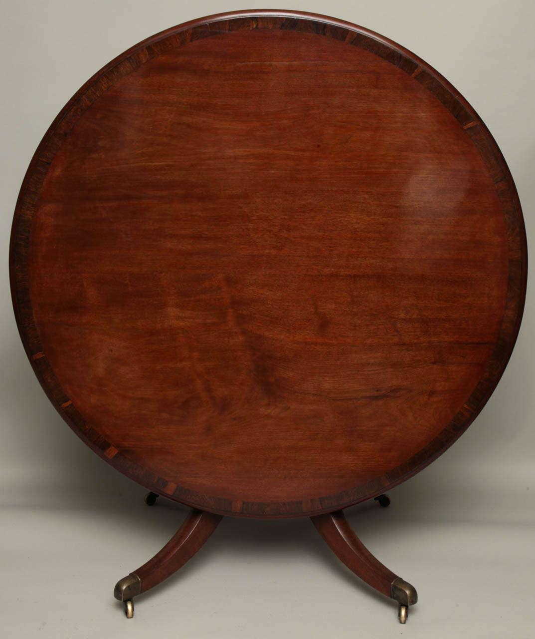 A very fine George III period solid and well figured mahogany breakfast table with rosewood banding, the bold top over urn shaft on lovely molded down swept legs ending in original brass castors, the whole with good rich color and patination.