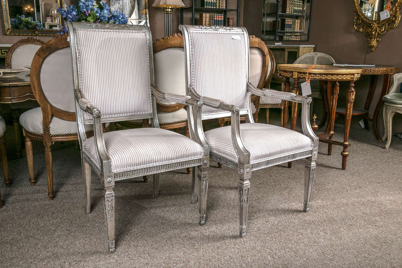 Louis XVI style silver gilt armchairs by Karges. A fine pair of striped upholstered arm chairs in the Louis XVI style both having a silver gilt aged appearance. Finely carved. 

The ability to transform wood into elegant furniture is a