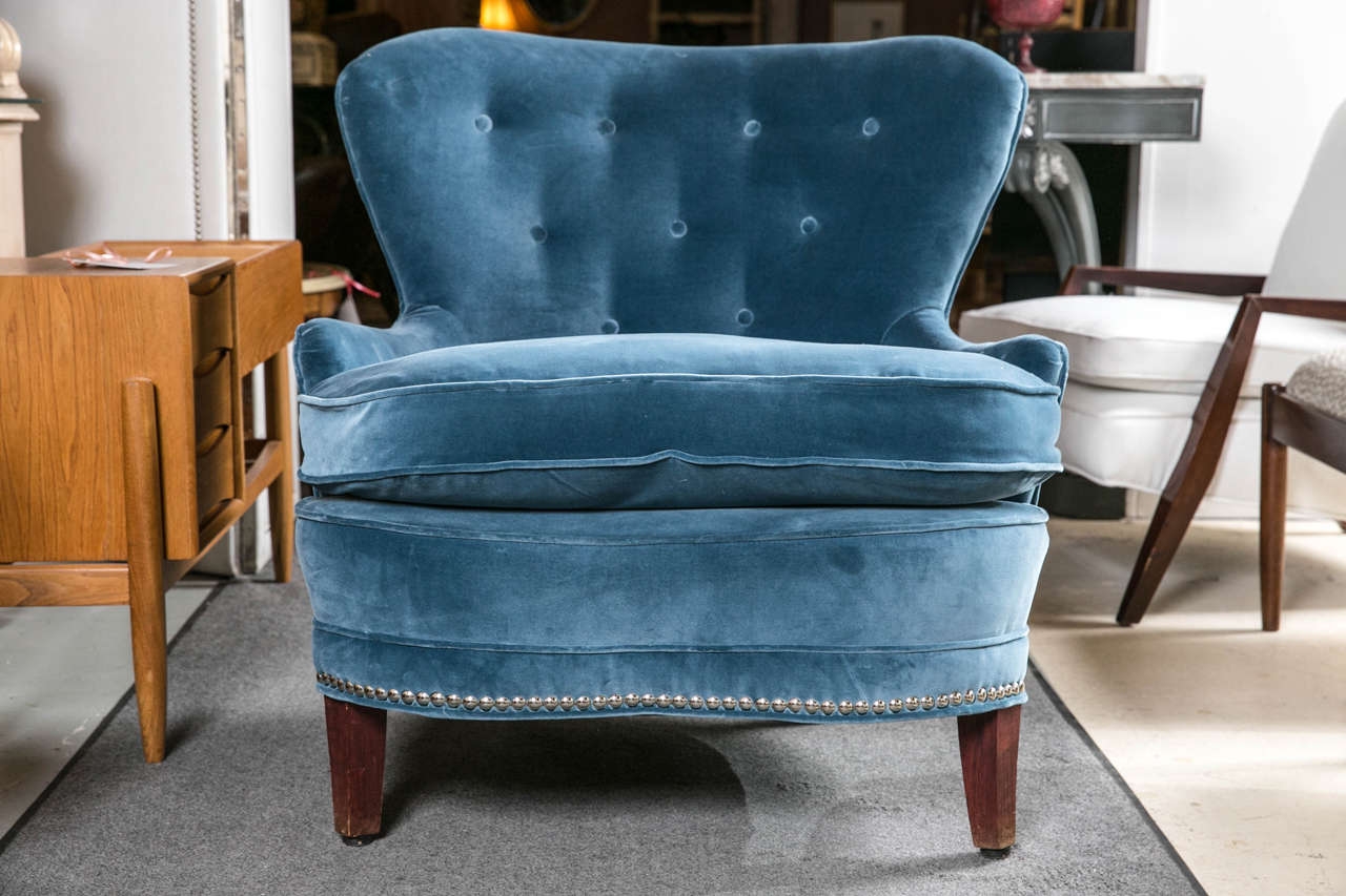 Blue velour Art Deco style Mid-Century Modern chairs. This fine pair of mid century modern lounge or living room chairs would add style and grace to any setting. The tufted back frames sitting on solid mahogany legs with all-over tacked frames.