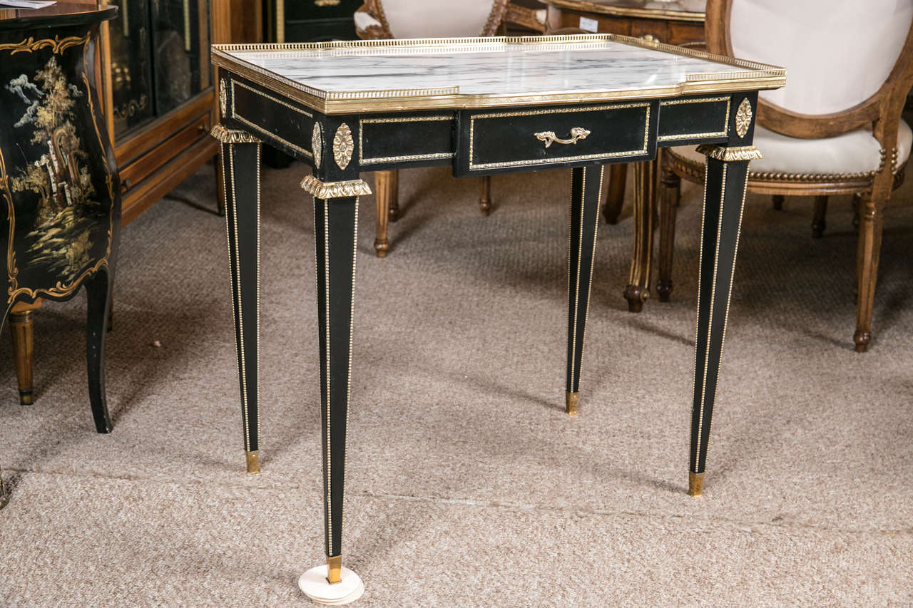 Bronze-mounted marble-top galleried stand or desk by Jansen. This fine Carrera white marble top framed in a pierced bronze gallery sits on a lovely refined base. The bronze Louis XVI style legs with corners running up the sides having bronze sabots