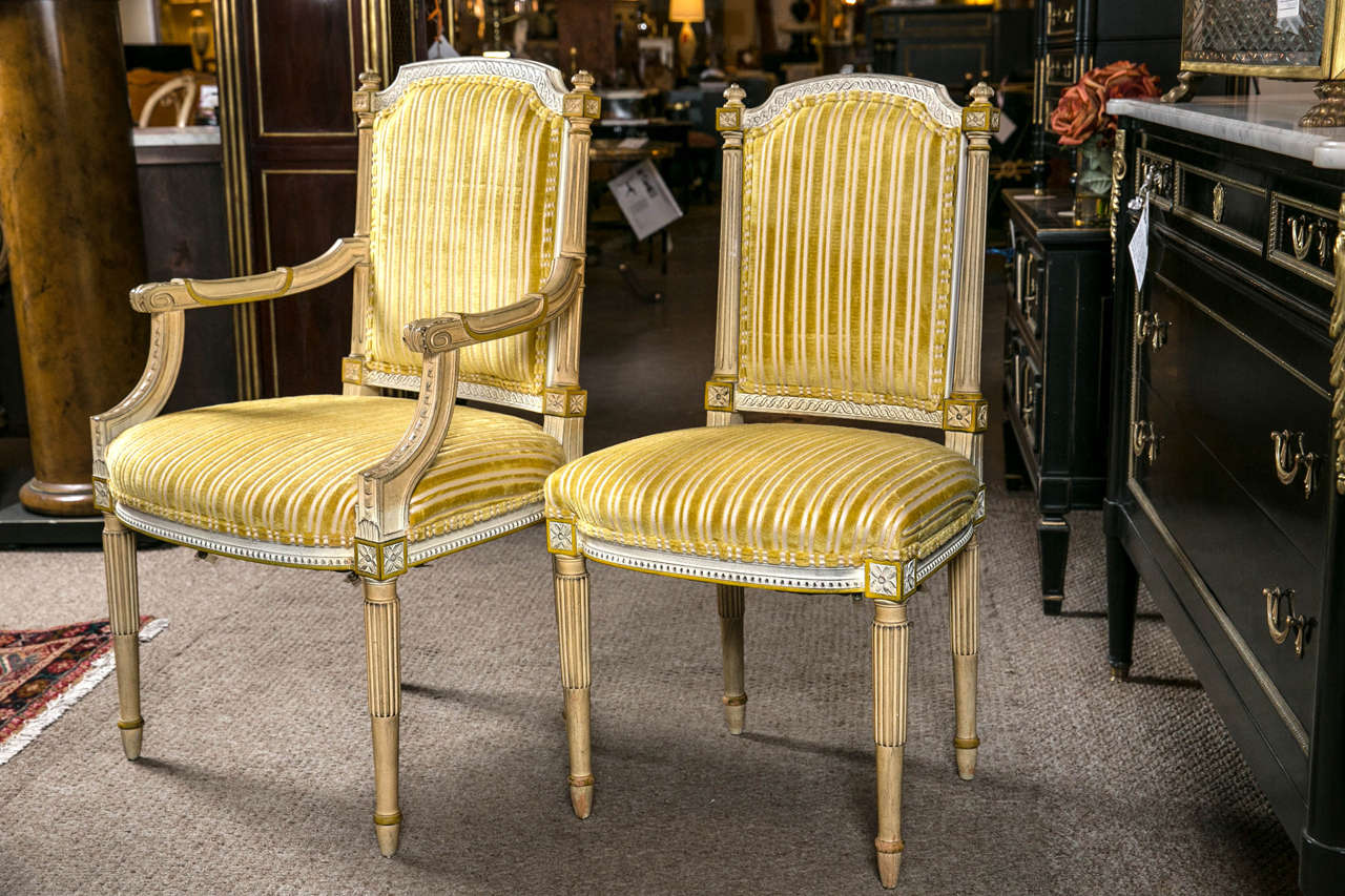 Set of six painted Louis XVI style dining chairs attributed to Jansen. Fine paint decorated and gilt gold Louis XVI style dining chairs. The tapering and reeded legs support a fine upholstered yellow and gold with white striped seats and padded
