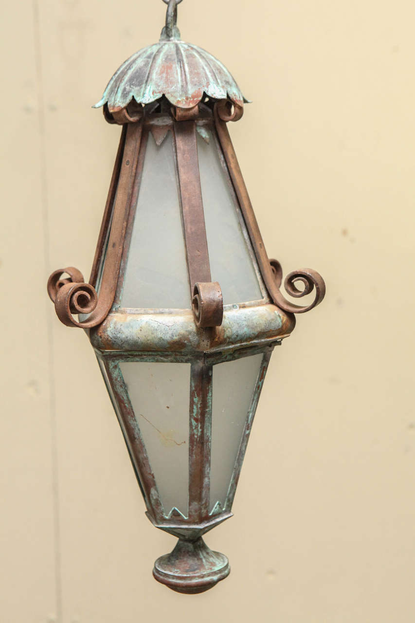 A pair of copper lanterns in an elongated diamond shape with iron scroll bands with natural patina.