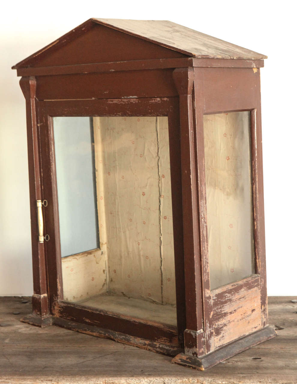 Handsome display case/ vitrine with glass swing out door and glass panels on side with remnants of original wallpaper lining.