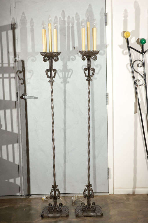 This pair of metal floor lamps from the 1930's have elegant decorative elements throughout with five candle holder lights. 