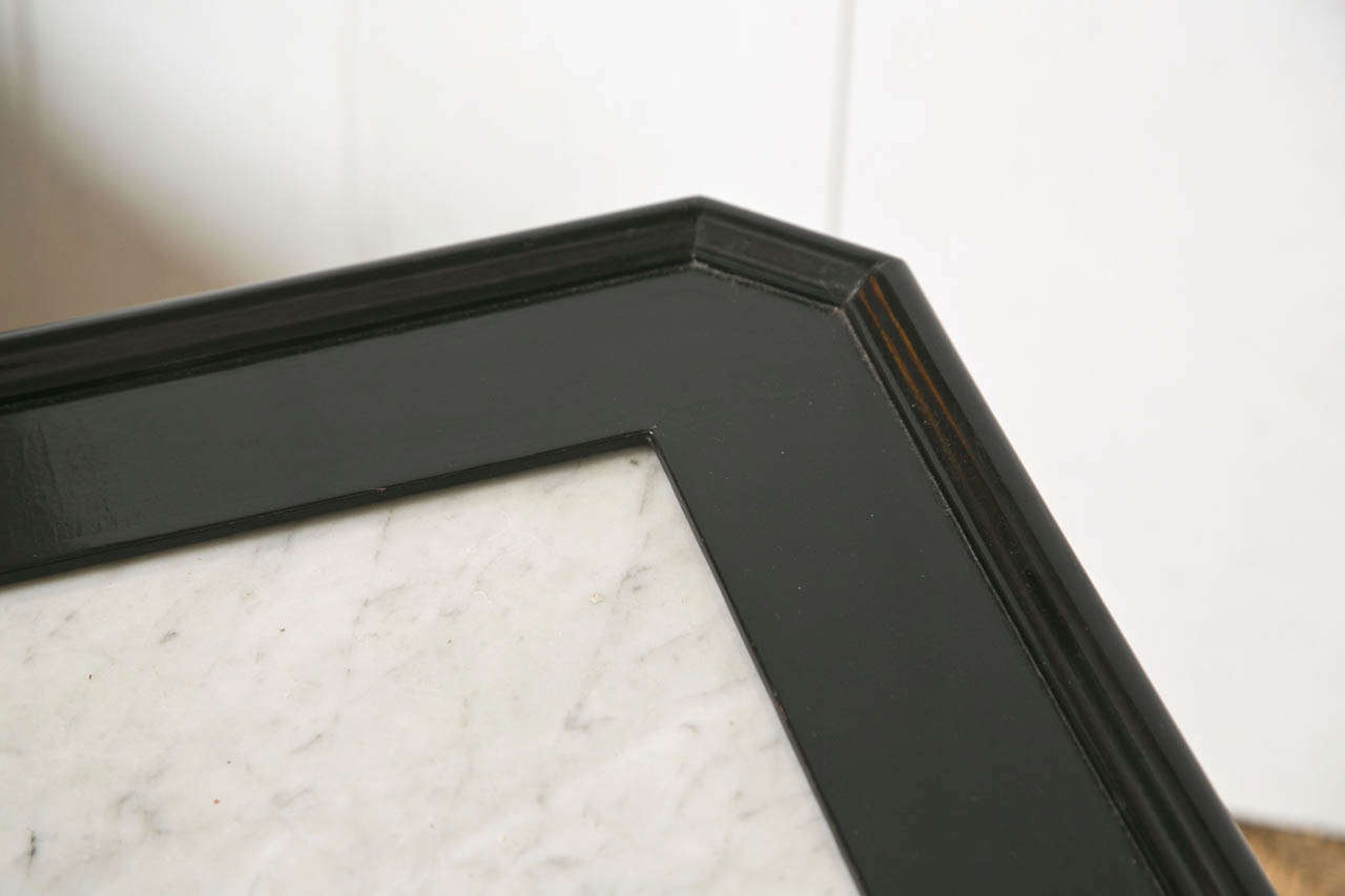 An ebonized and bronze-mounted square coffee low table. The bronze sabot feet supporting a set of tapering legs. The marble top with a framed border, by Maison Jansen. The top marble has been broken and repaired. The repair is difficult to