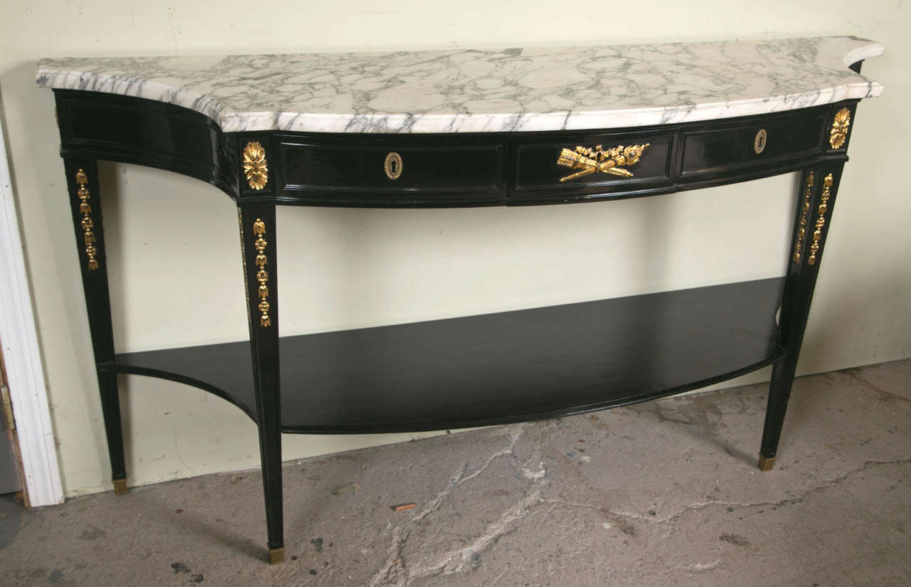Fine Hollywood Regency Style Demi Lune by Maison Jansen. Ebonized case sitting on bronze sabots leading to leaf decorated tapering legs supporting a fine demilune shaped marble top. The center scroll & torch design flanked by a pair of drawers. The