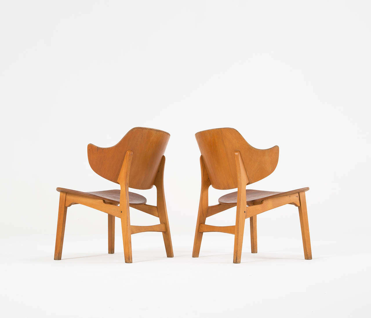 Lounge chairs in plywood, by lb Kofod-Larsen, Denmark 1950s. 

The distinctive feature of this pair of plywood easy chairs is its beautifully curved large back which continues in the armrests in one piece. The beech and teak really compliment each