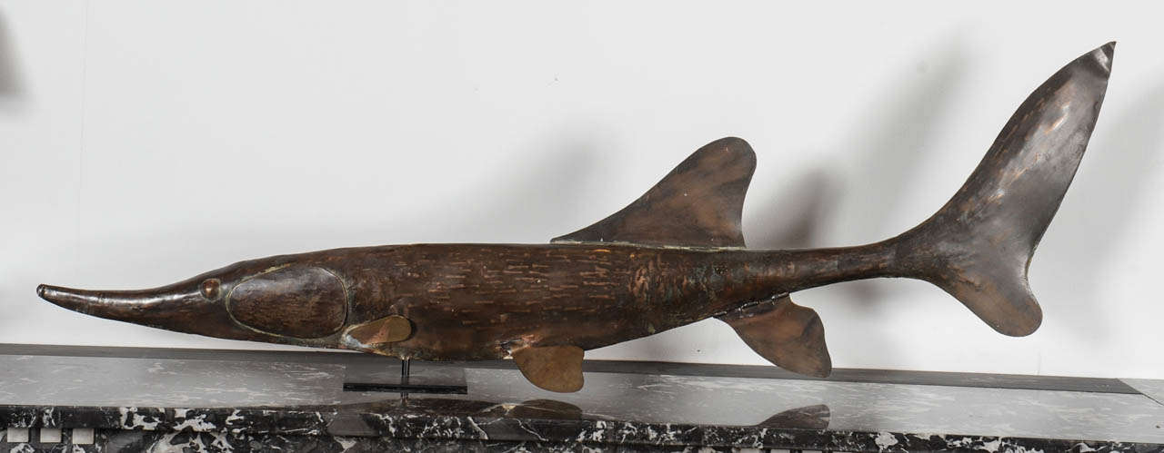 Hand hammered copper wind vane in the form of a sturgeon.