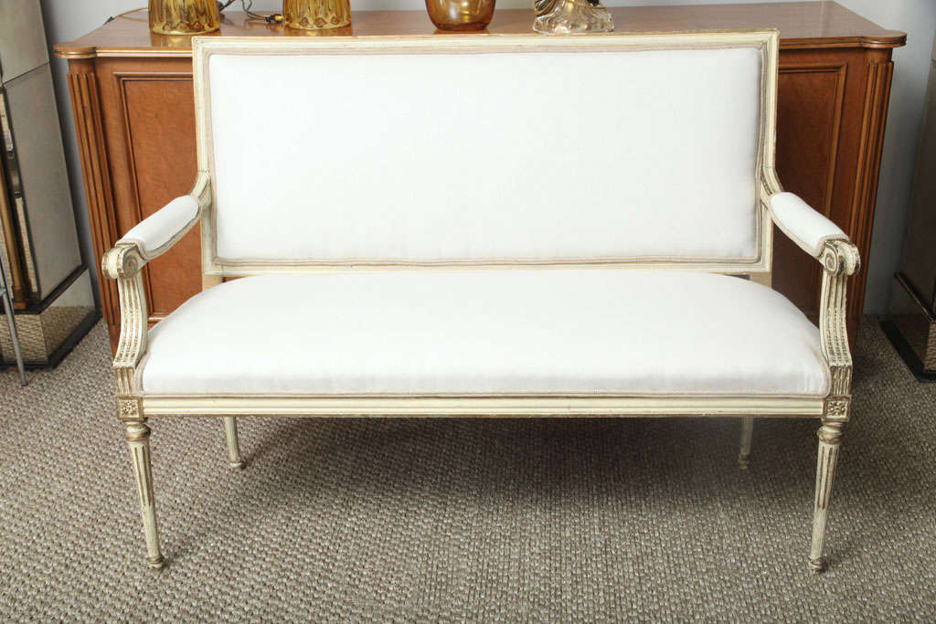 A painted and parcel gilt Louis XVI Style settee with a rectangular back and curved back arms--a piece with understated style