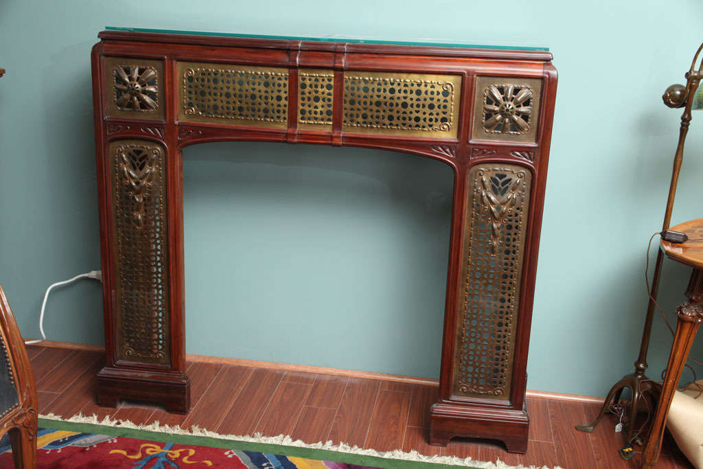 A French Art Nouveau carved mahogany & bronze filigree fire surround by, Jules Cayette decorated with elaborate gilt bronze art nouveau filigree. The fire surround is signed, 