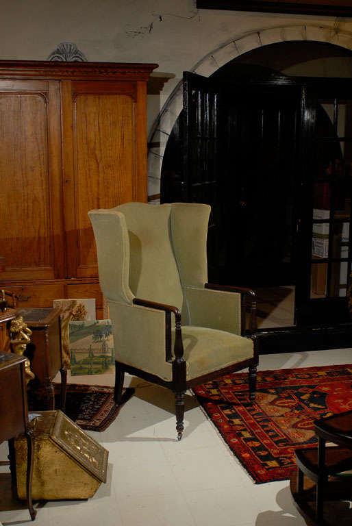 Late 19th Century American Federal-Style Mahogany Wing Chair with arched back and shaped wings.  The mahogany reeded arms continue and taper into turned reeded legs raised on brass casters. Upholstered in a green velvet.