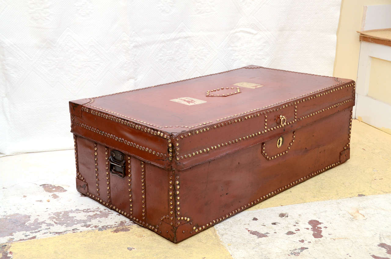 MID TO EARLY 19TH CENT. COLONIAL CAMPHOR TRUNK COVERED WITH LEATHER ( LATER PAINTED AN OXBLOOD COLOR) POSSIBLY FOR THE FRENCH MARKET--- BECAUSE OF THE TYPE OF LOCK USED.EDGED IN BRASS NAIL HEADS.
MAKES A GREAT COFFE TABLE