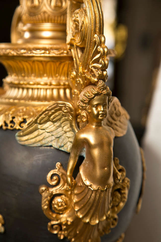gilded and patinated bronze , 7  candle arms, scrolled handles adorned with winged putti, the center section of patinated bronze adorned with  winged putti riding  griffins, foliate decoration, and winged lions above the concave bases.Please feel